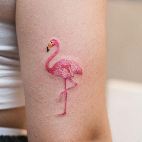 A miniature, watercolor flamingo watercolor tattoo